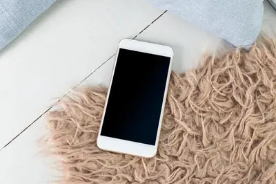 White smartphone with a black screen lying on a rug