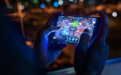Person playing a mobile game on a smartphone in a dark room